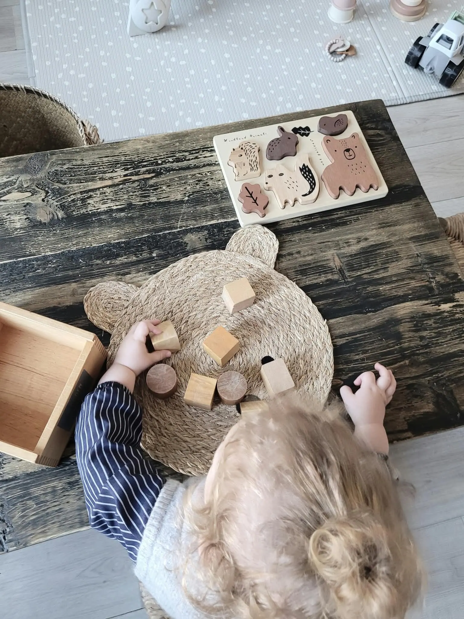 Kind speelt binnen aan tafel met houten dieren-puzzel en blokken