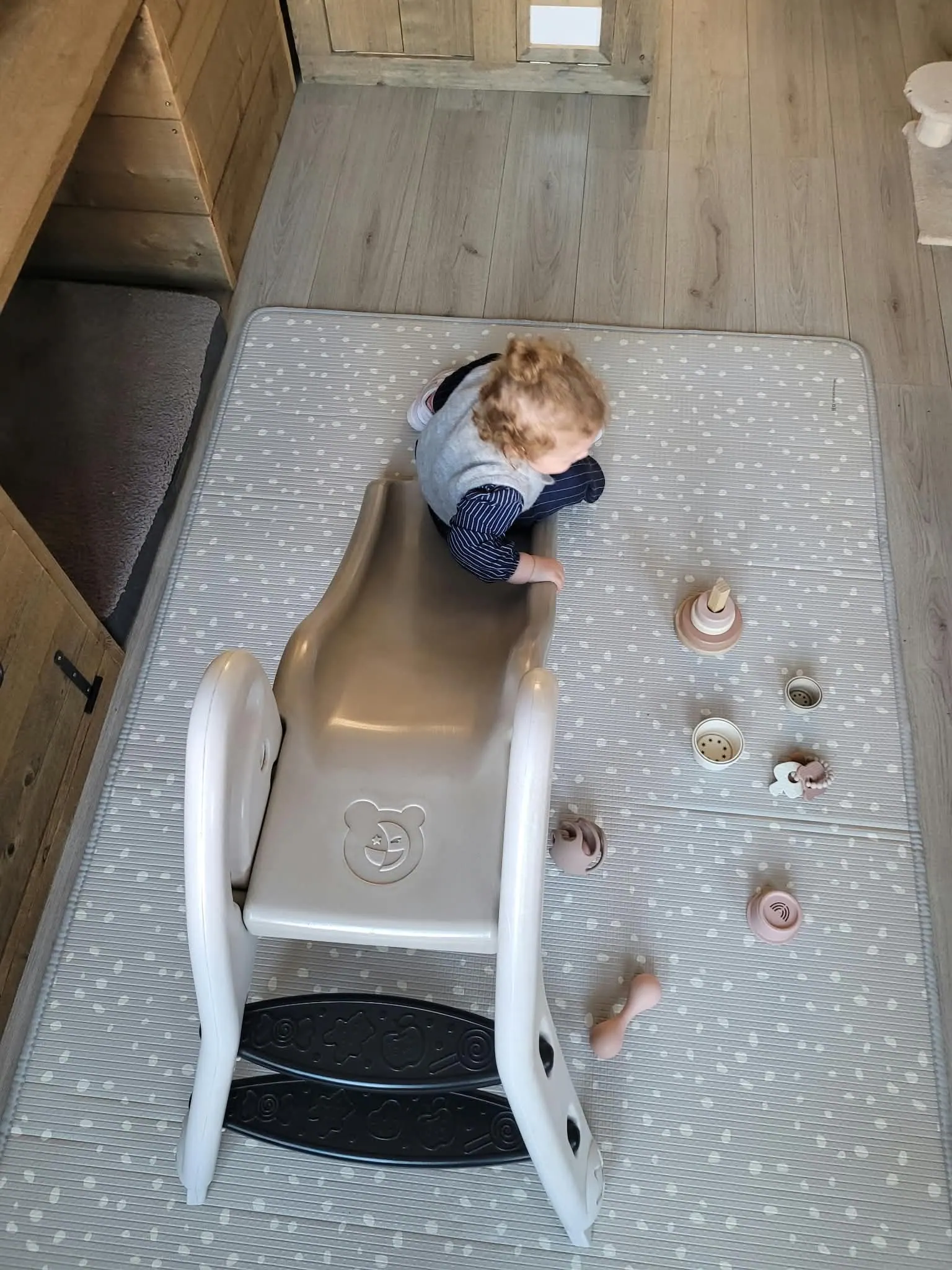 Peuter speelt binnen op een glijbaan op een speelkleed