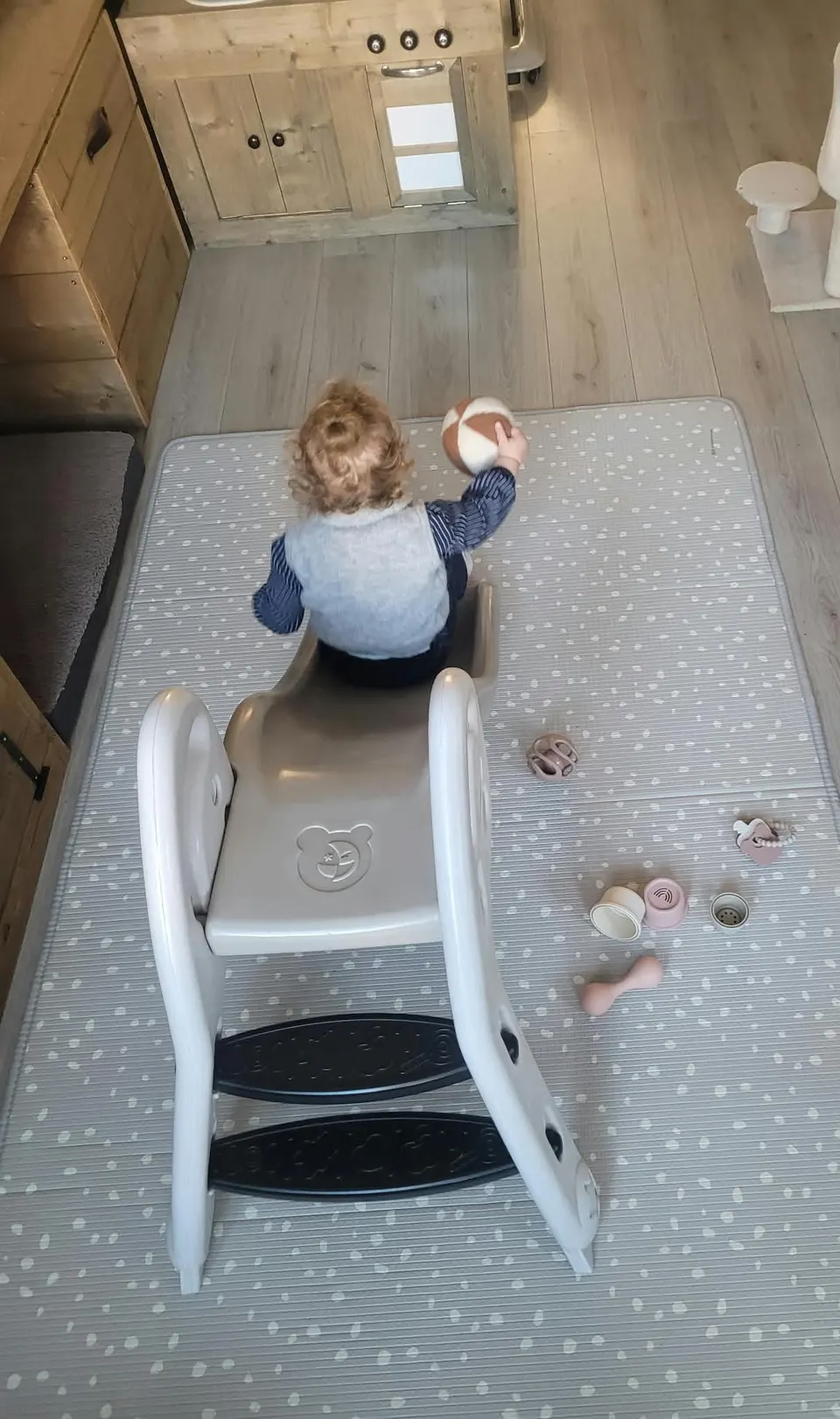 Peuter speelt met bal bij een glijbaan op speelmat