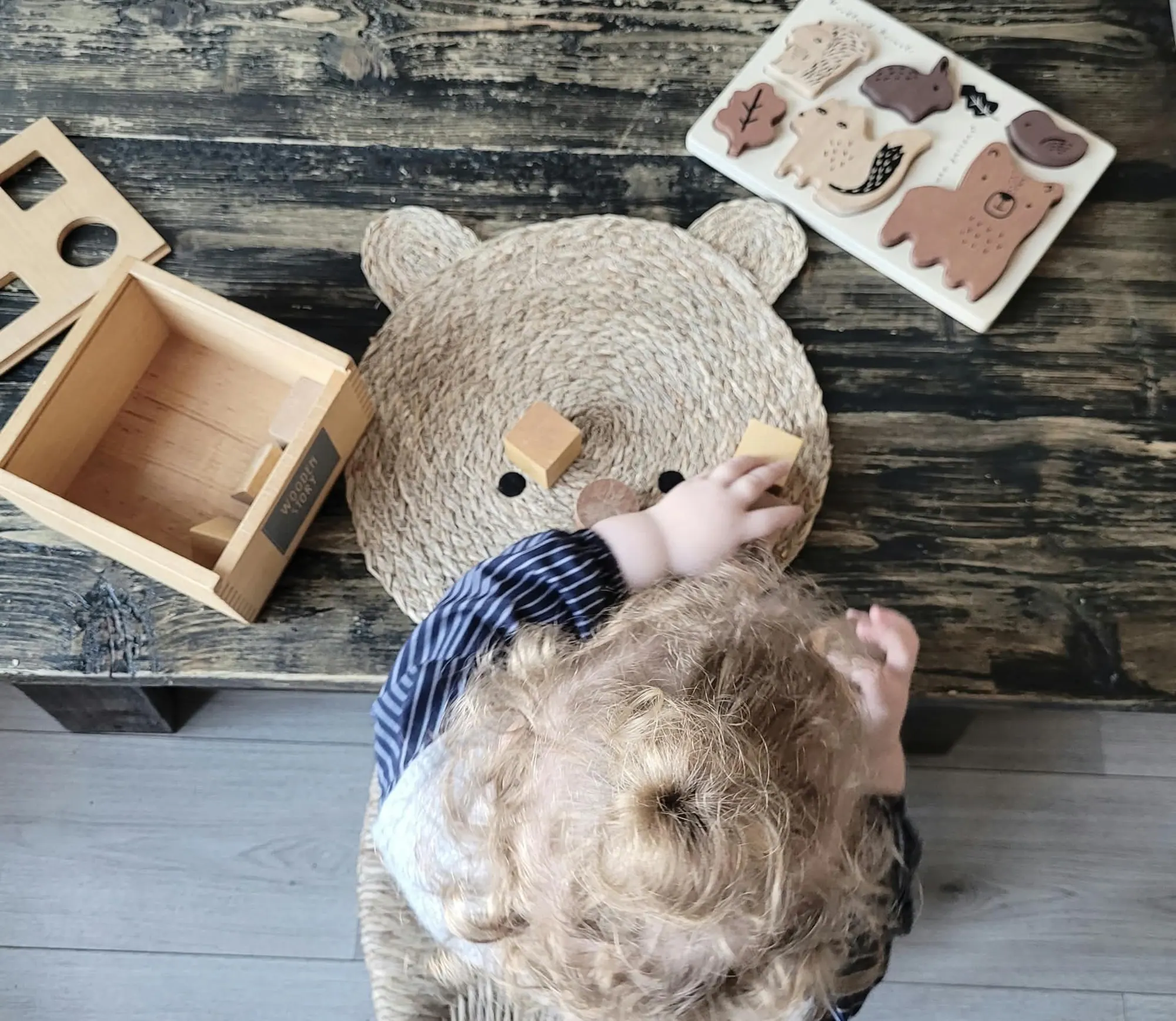 Kind met krullen speelt met houten dierenpuzzel aan tafel