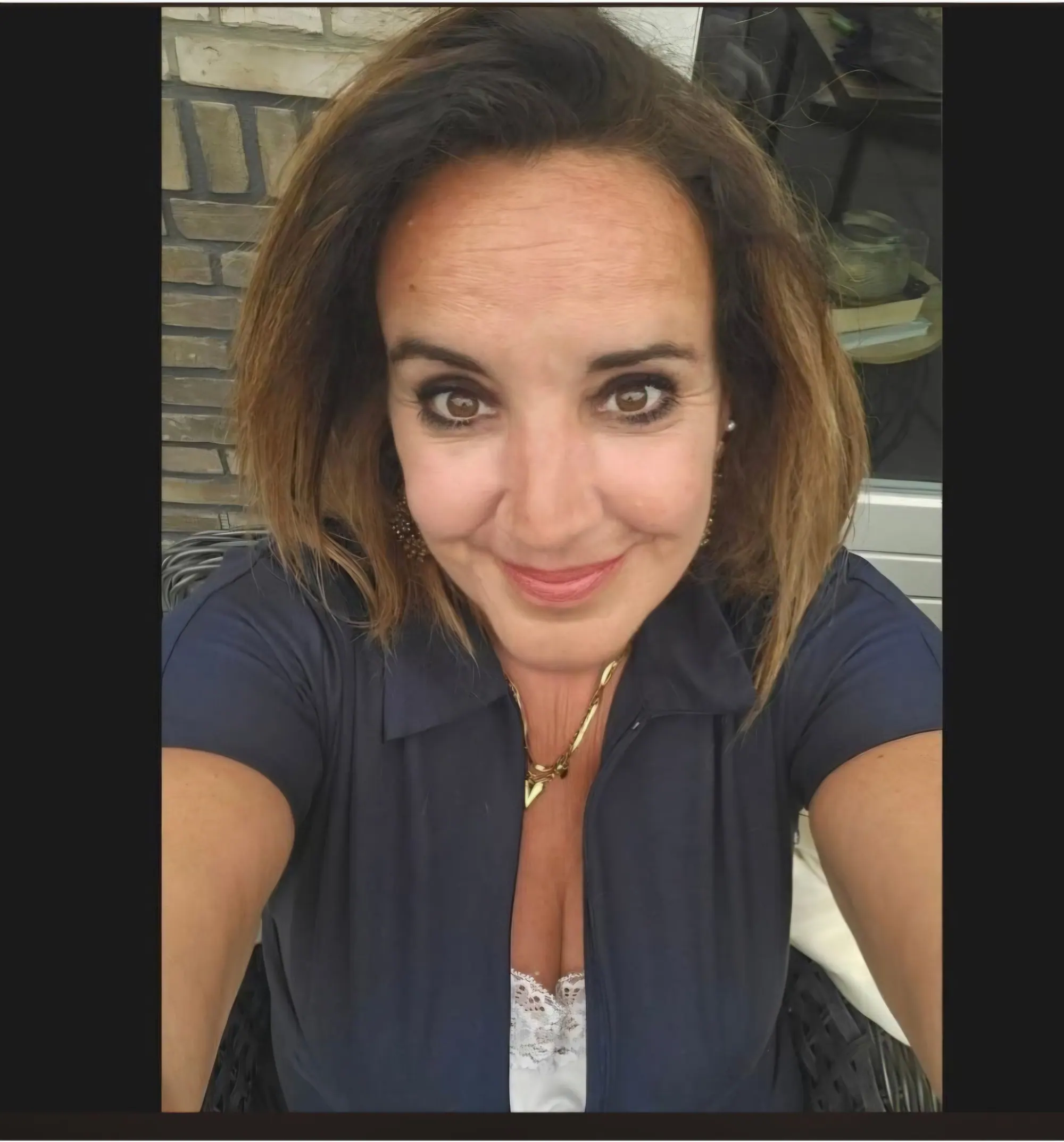 Lachende vrouw met halflang bruin haar, selfie buiten